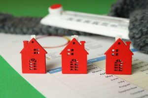 Three small toy houses on top of HVAC financing paperwork.