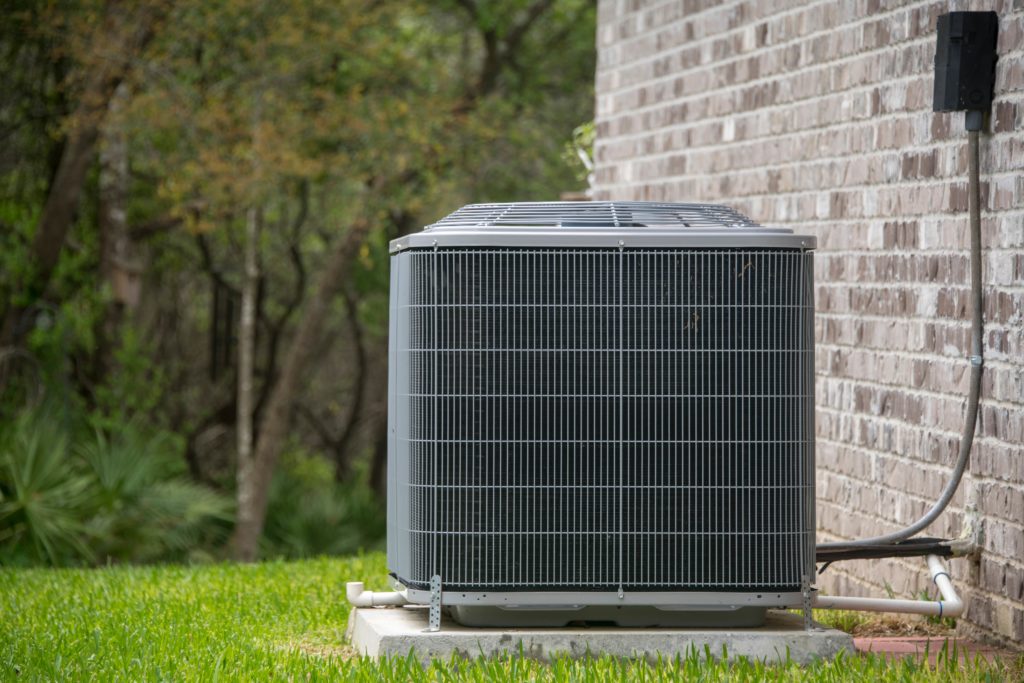 An outdoor AC unit installed on a concrete slab outside a home.